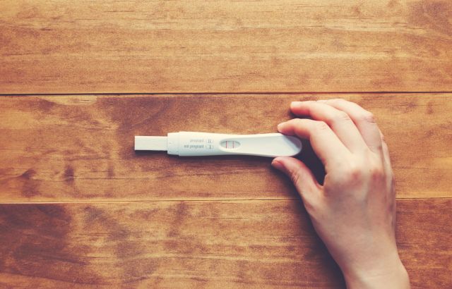 Eine Hand hält einen Schwangerschaftstest